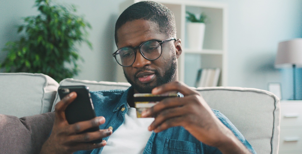 man shopping on his phone holding his credit card